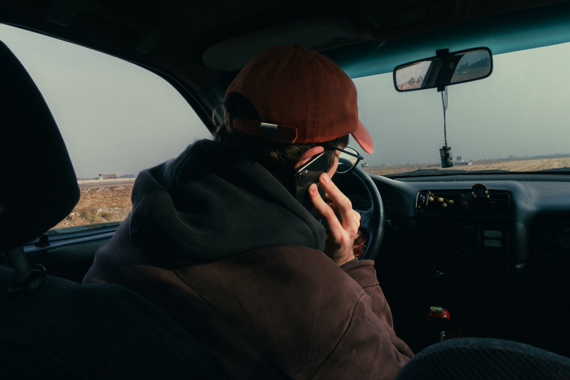 Person in car wearing a hat and glasses.